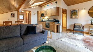 A cozy living room with a sofa, a dining area with a table and chairs, a kitchen with wooden cabinets, and a bathroom with a mirror. - Modern Comfortable Apartment with Balcony and Garage. Great Location for Skiing. (Samoëns)