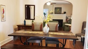 Un comedor con una mesa de madera, dos sillas y un florero con flores.