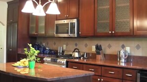 Una cocina con armarios de madera, un microondas de acero inoxidable, una estufa y una planta verde sobre la encimera.