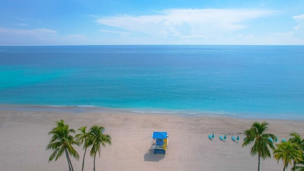 Enjoy a secluded beach experience with a lifeguard station and shaded areas under colorful umbrellas.
