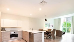 A modern kitchen with a central island, built-in oven, and white cabinetry.