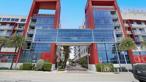 Un hotel moderno con fachada roja y blanca, amplios ventanales de vidrio y una entrada central.