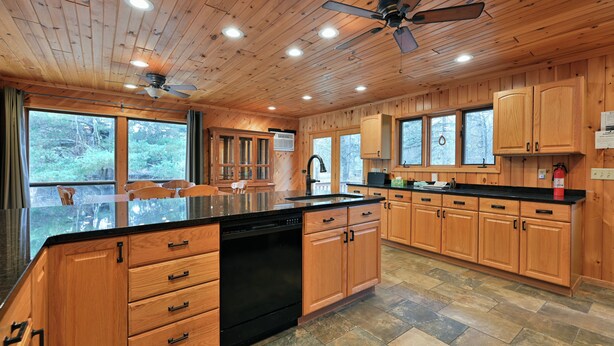 A spacious kitchen with wooden cabinets, a large island, and a ceiling fan. - Kenny Lodge (Cable)