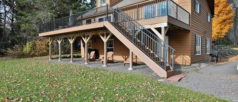 Une cabane en bois à deux étages, dotée d’un balcon et d’un espace extérieur aménagé pour s’asseoir.