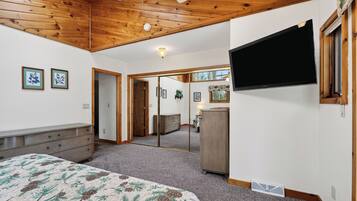 A bedroom with a bed, dresser, mirror, and a TV mounted on the wall.