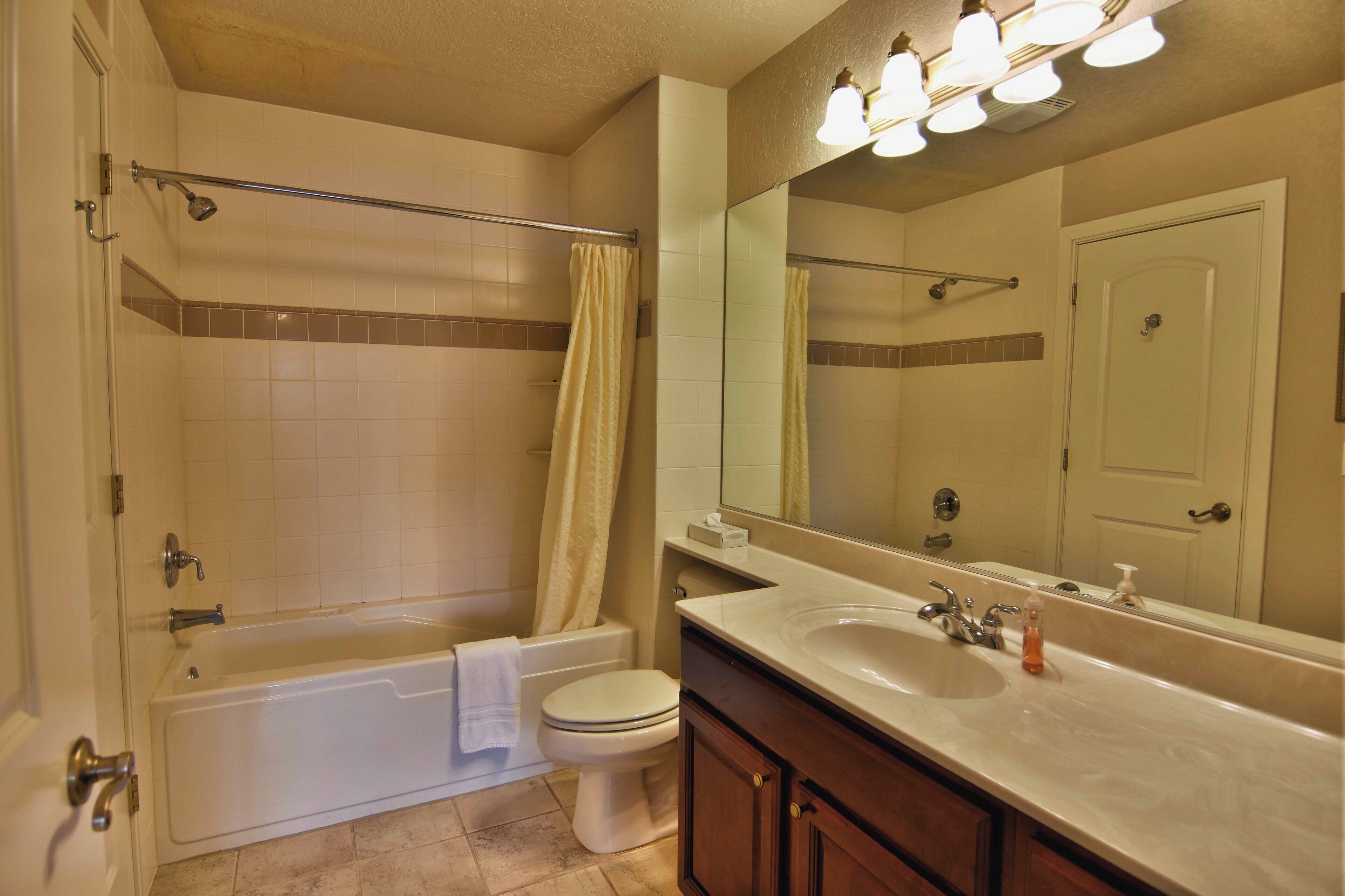 A bathroom with a bathtub, toilet, sink, and a large mirror.