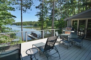 A deck with outdoor furniture, a grill, and a view of a lake. - Serenity on Lake Owen (Cable)