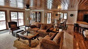A spacious living room with a wooden ceiling, large windows, and a dining area. - Peace of Mind on Namakagon (Cable)
