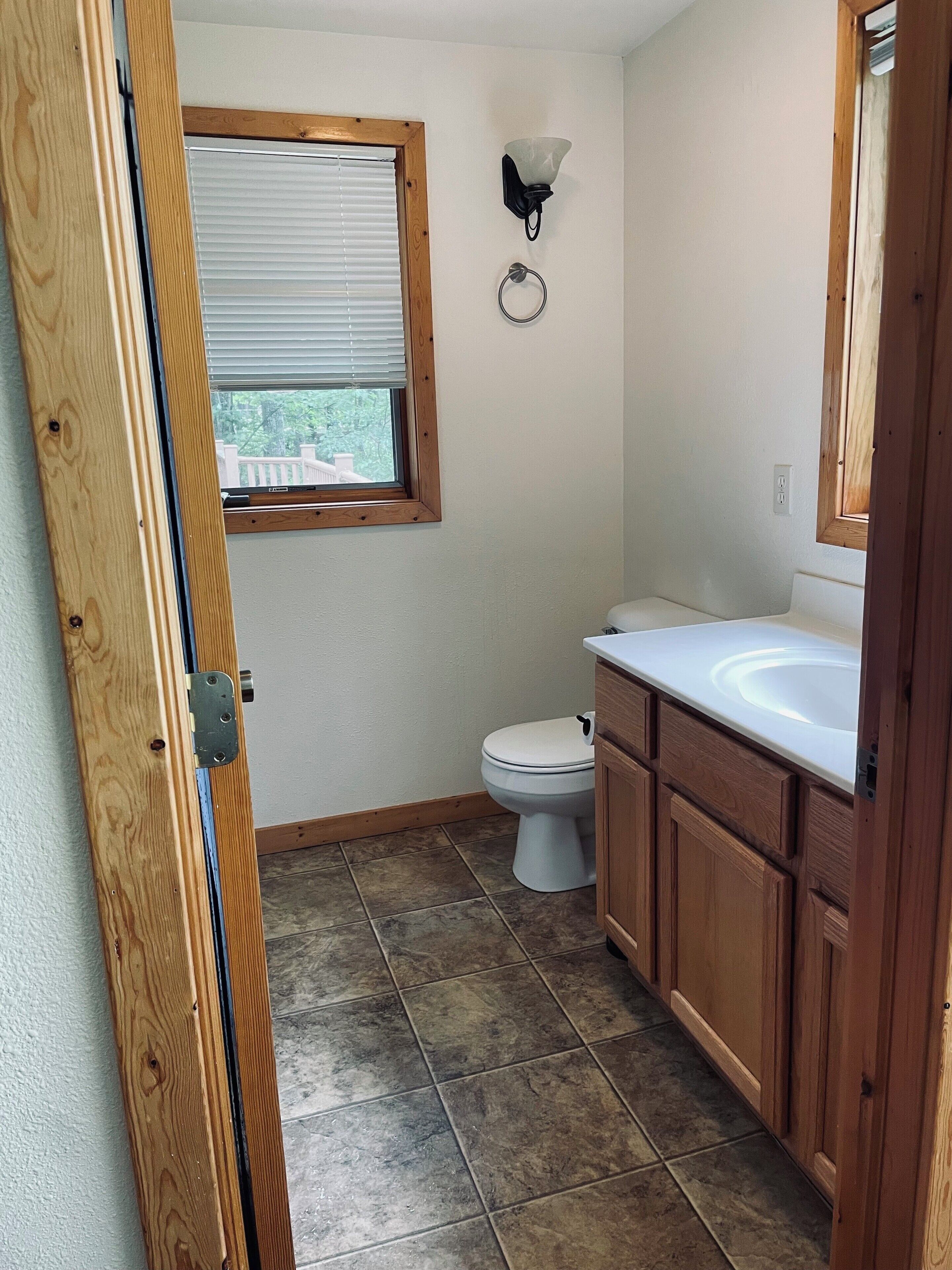 A small bathroom with a toilet, a sink, and a window.