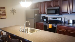 A kitchen with a granite countertop, stainless steel sink, and a double oven. - Unit 311 1 BD/ 1 BA Condo (Birchwood)