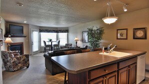 A spacious living area with a kitchen island, dining table, and comfortable seating. - Unit 311 1 BD/ 1 BA Condo (Birchwood)