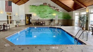 Une piscine intérieure avec un plafond en bois, une fresque représentant un paysage et un drapeau accroché au mur.