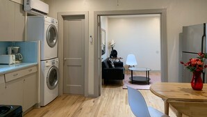 A compact kitchen with a washing machine, a coffee maker, and a refrigerator.