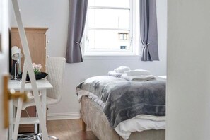 A bedroom with a bed, a desk, a chair, and a window with curtains. - GuestReady - 2BR in Leith w Ocean Views & Parking (Leith)
