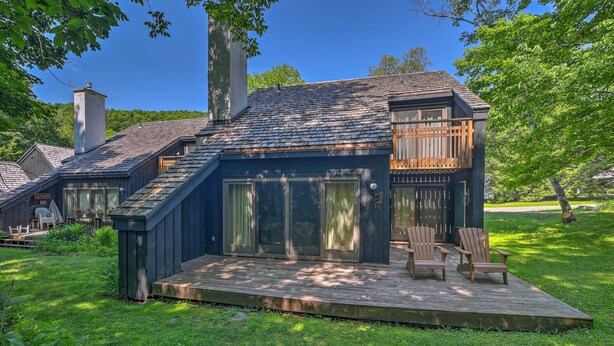 A modern house with a deck, large windows, and a chimney. - Waitsfield Condo w/ Pool & On-Site Trail Access! (Waitsfield)