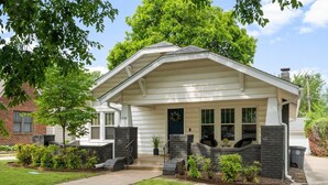 Ein eingeschossiges Haus mit einer Veranda, Ziegelstufen und einem kleinen Garten.