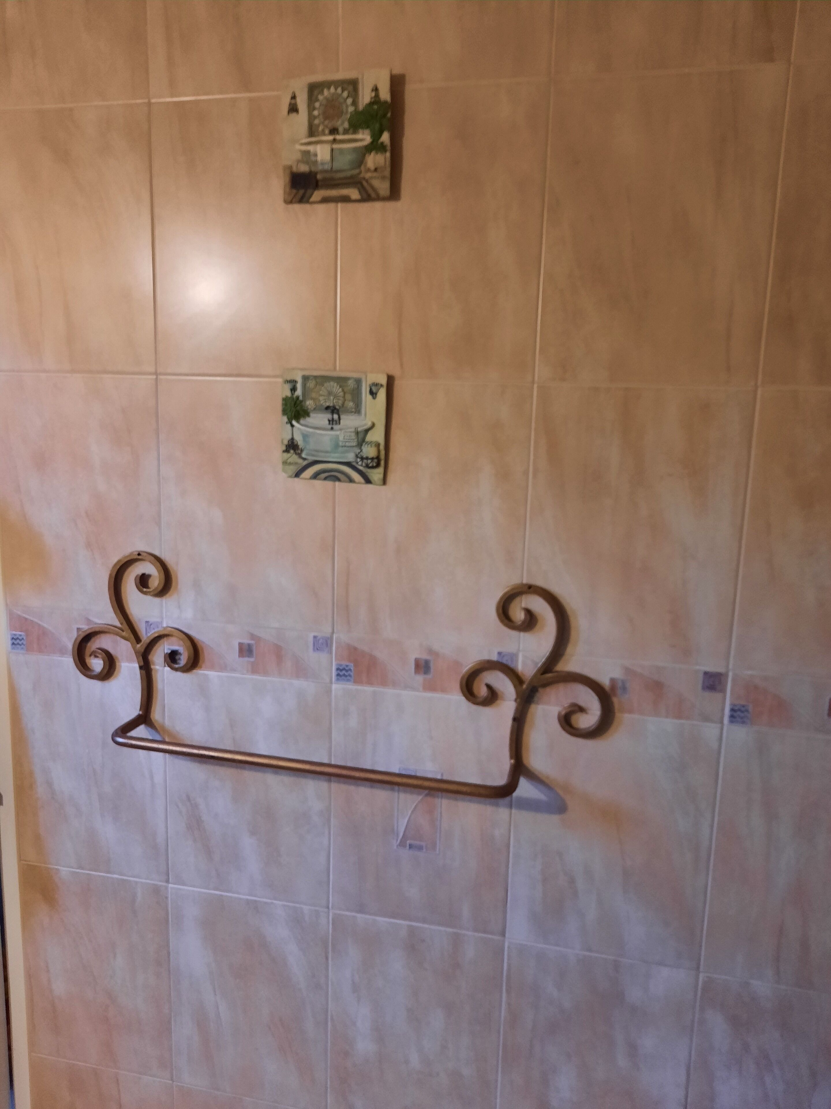 Une salle de bain équipée d’un porte-serviettes, d’un petit objet décoratif et d’un luminaire fixé au mur.