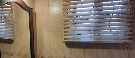 A bathroom with a granite sink, a mirror, and wooden blinds.