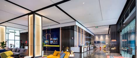 A modern lobby with a yellow sofa, green armchair, and a reception desk.