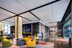 Eine moderne Lobby mit einem gelben Sofa, einem grünen Sessel und einem Empfangstresen.