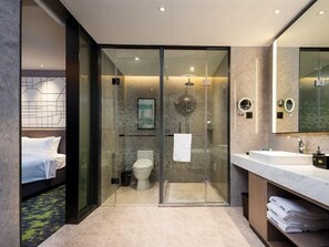 A modern bathroom with a glass-enclosed shower, a white sink, and a large mirror.