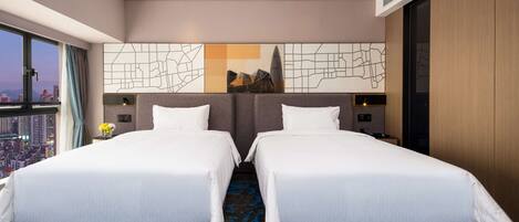 Une chambre d’hôtel avec deux lits, une vue sur la ville, une grande œuvre d’art abstrait accrochée au mur et une moquette à motifs bleus.