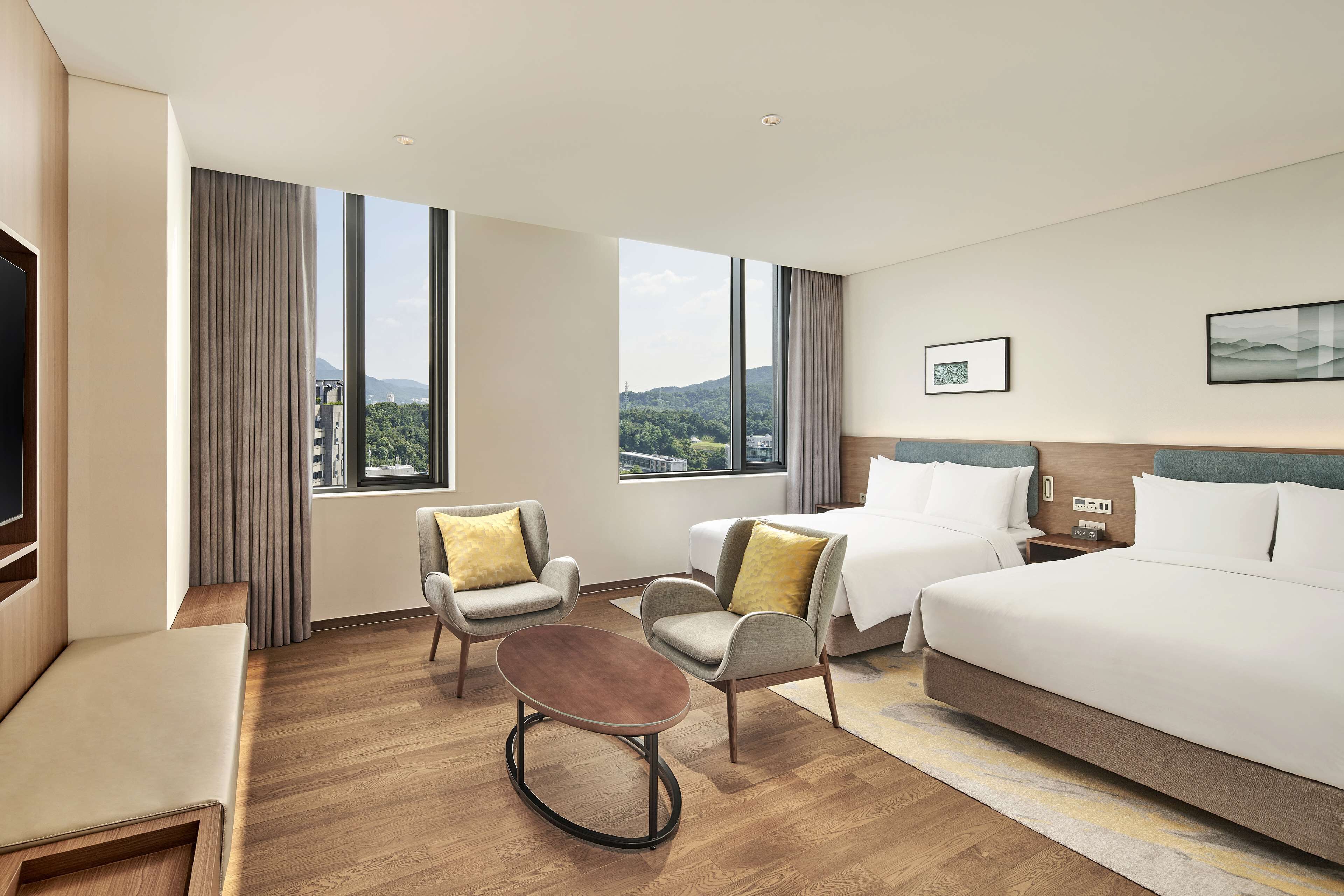 A hotel room with a large bed, two armchairs, a small table, and a TV.