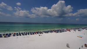 A beach with white sand and turquoise water, lined with umbrellas and beach chairs. - Beach Front Condo with ocean and pool view!!! (Miramar Beach)