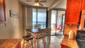 A kitchen with a dining area, a ceiling fan, and a view of the ocean. - Beach Front Condo with ocean and pool view!!! (Miramar Beach)