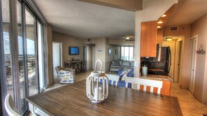 A spacious living area with a wooden dining table, a decorative lantern, and a kitchen area with a refrigerator and stove. - Beach Front Condo with ocean and pool view!!! (Miramar Beach)