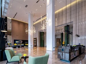 A modern lobby with a reception desk, seating area, and a large window. - Hampton BY Hilton Nanning Wuxiang (Nanning)