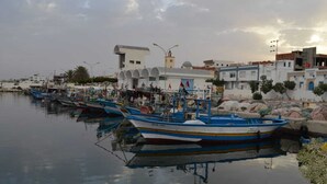 A harbor with several boats docked, a building with a dome, and a clear sky. - Tunisia, royal duplex (Salakta)