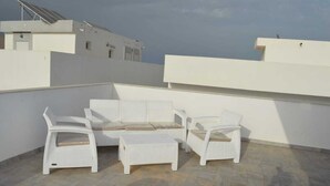 A rooftop terrace with a white wicker sofa set, a small table, and a chair. - Tunisia, royal duplex (Salakta)