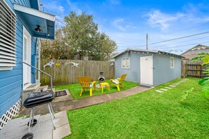 A backyard with a barbecue grill, two yellow chairs, and a small shed.
