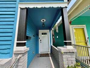 A blue house with a white door and a small porch.