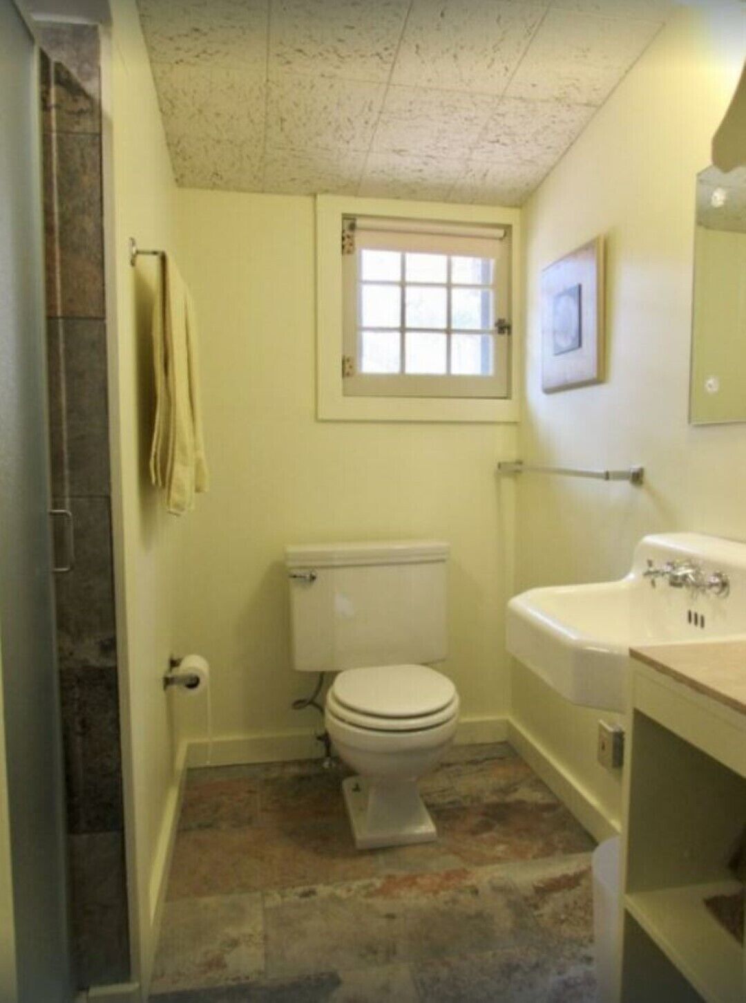 Ein Badezimmer mit Toilette, Waschbecken und einem kleinen Fenster.