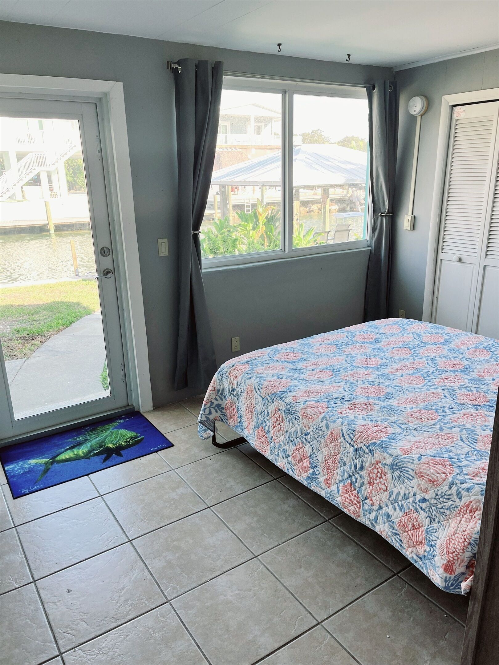 Ein Schlafzimmer mit Bett, Fenster, Tür und Blick ins Freie.