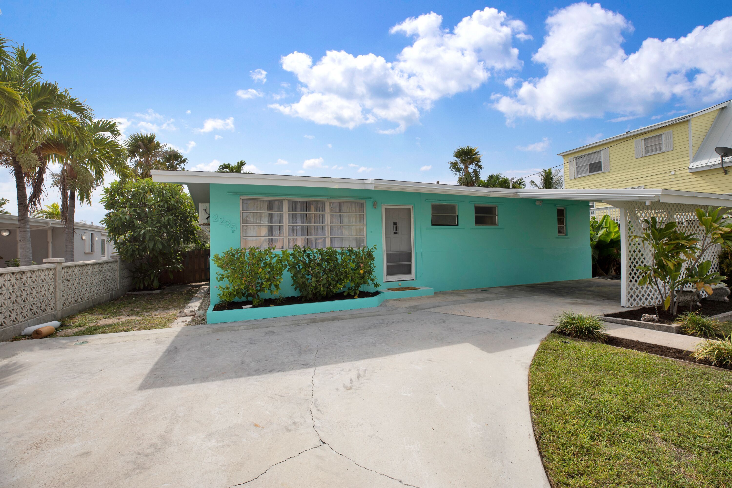 A single-story house with a teal exterior, a front garage door, and a small porch area.