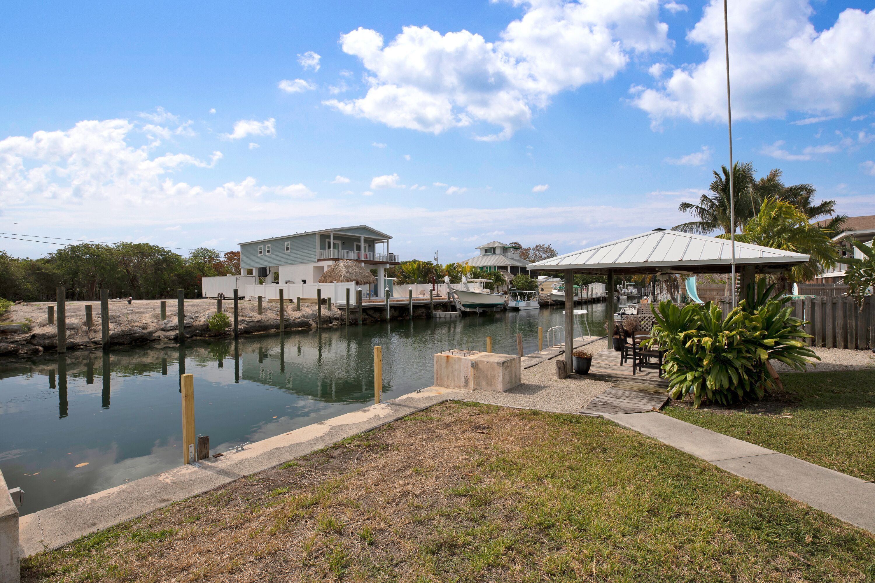 A waterfront property with a dock, a covered patio, and a small pool.