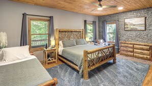Ein Schlafzimmer mit Holzboden, einer Steinwand, einem Bett mit Holz-Kopfteil, einem Schminktisch und einem Gemälde.