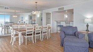 A spacious living room with a dining area, a gray sofa, and a chandelier. - Life is better at the Beach (Daytona Beach)