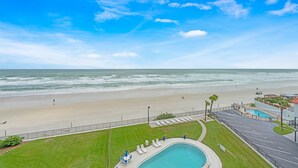 A beachfront hotel with a swimming pool, a beach view, and a parking area. - Life is better at the Beach (Daytona Beach)