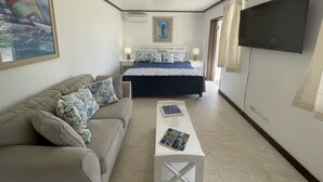 Ein Hotelzimmer mit einem Bett, einem Sofa, einem Couchtisch, einem Fernseher und einem Bild an der Wand.