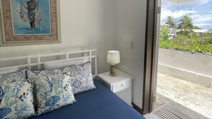 Ein Schlafzimmer mit Bett, Kissen, Nachttisch, Lampe und einem Gemälde an der Wand.