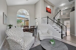 A spacious living room with patterned sofas, a dining area, and a staircase leading to an upper level. - Gorgeous SURPRISE GEM 2 Miles to Baseball Stadium (Surprise)