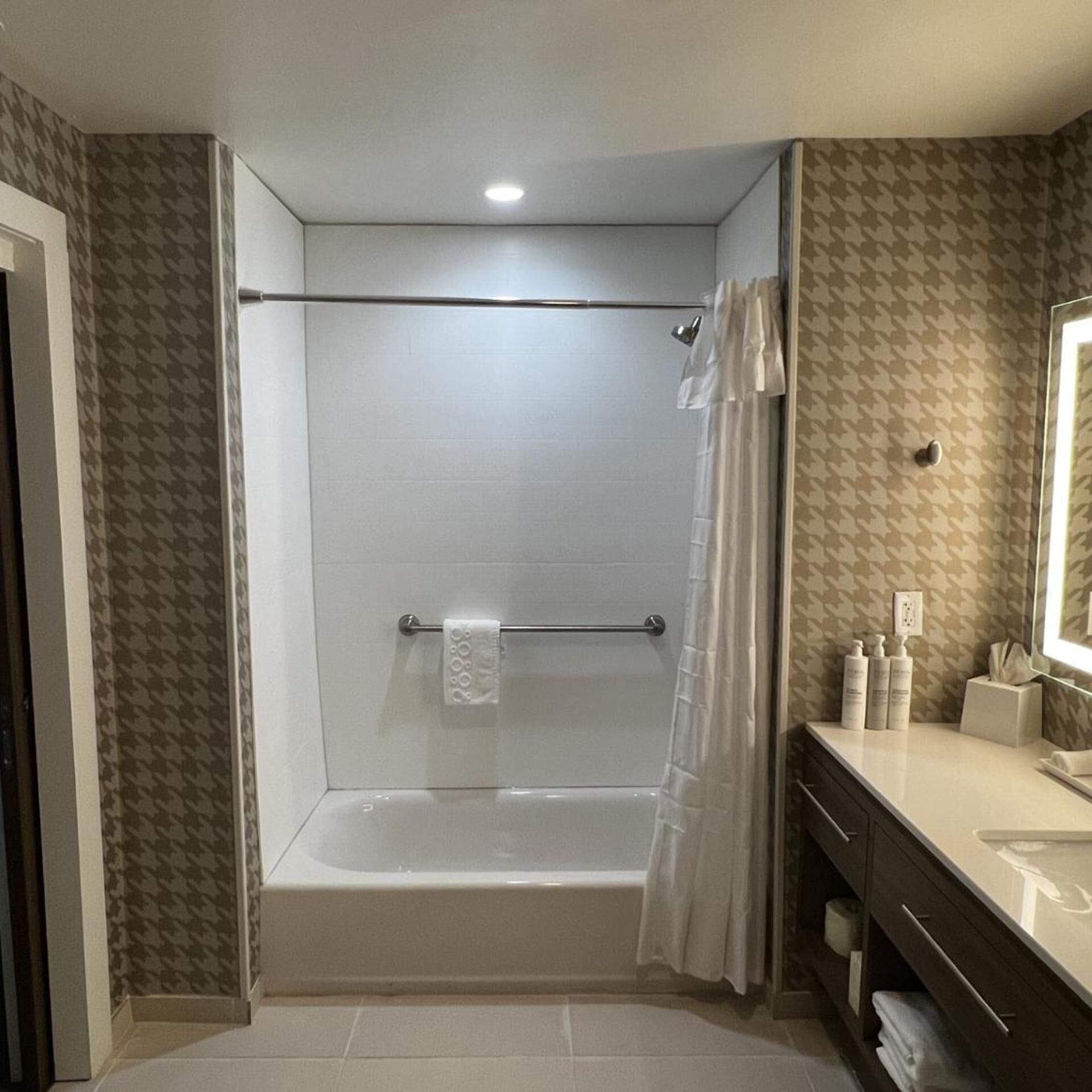 A bathroom with a shower, a towel rack, a toilet, and a sink with toiletries.