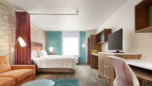 A hotel room with a bed, a desk, a chair, a TV, and a window. - Home2 Suites BY Hilton Hinesville (HINESVILLE)