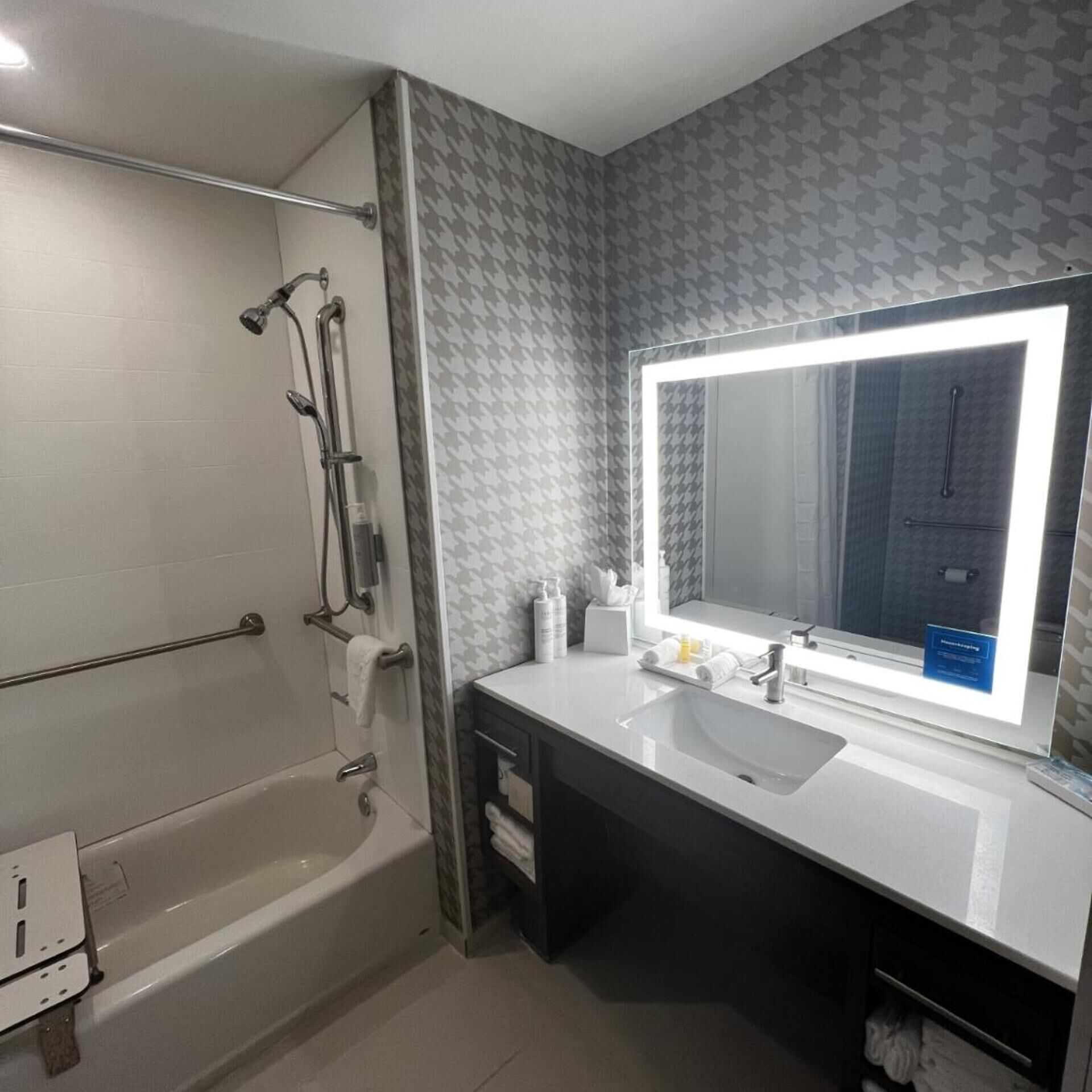 Ein modernes Badezimmer mit einer Badewanne, einem Waschtisch mit Becken und einem großen Spiegel.