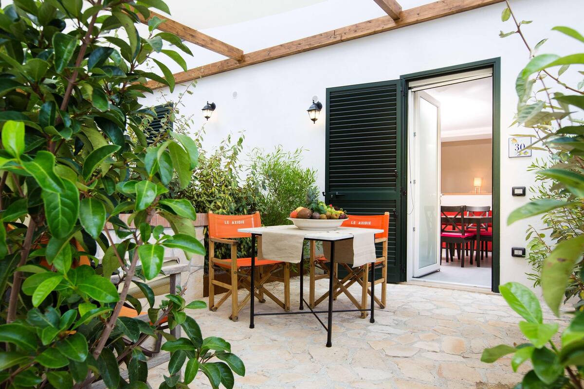 An outdoor patio with a table and chairs, a stone floor, and a door leading to an interior space.