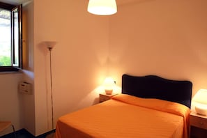 A room with a bed, a nightstand, a lamp, a window, and a wall-mounted light fixture. - Residence Le Axidie Sure Hotel Collection by BW (Vico Equense)